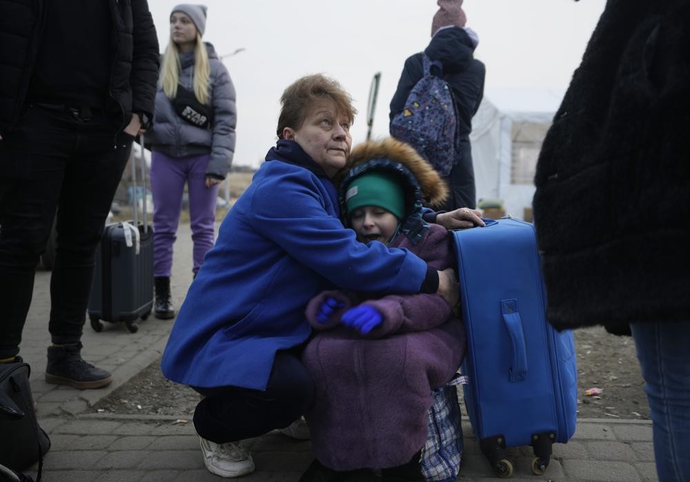 A woman holds a small girl at a border crossing, up as refugees flee a Russian invasion, in Medyka, Poland, Thursday, March 3, 2022. The U.N. refugee agency said Thursday at least 1 million people have fled Ukraine since Russia’s invasion a week ago, an exodus without precedent in this century for its speed. (AP Photo/Markus Schreiber)