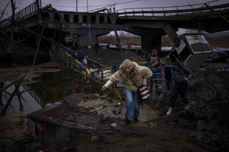 A woman runs as she flees with her family across a destroyed bridge in the outskirts of Kyiv, Ukraine on March 2. Russia renewed its assault Wednesday on Ukraine’s second-largest city in a pounding that lit up the skyline with balls of fire over populated areas, even as both sides said they were ready to resume talks aimed at stopping the new devastating war in Europe. (AP Photo)