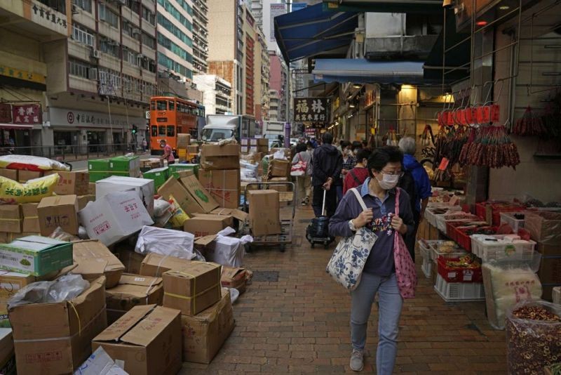 A woman wearing a face mask walks at a local market in Hong Kong, Wednesday, March 16, 2022. (AP Photo)