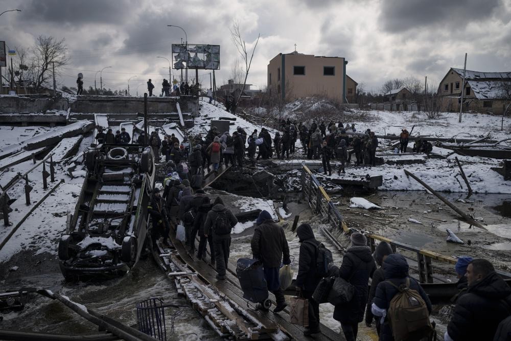 FILE - Ukrainians cross an improvised path under a destroyed bridge while fleeing Irpin, in the outskirts of Kyiv, Ukraine, Tuesday, March 8, 2022. (AP Photo/Felipe Dana)