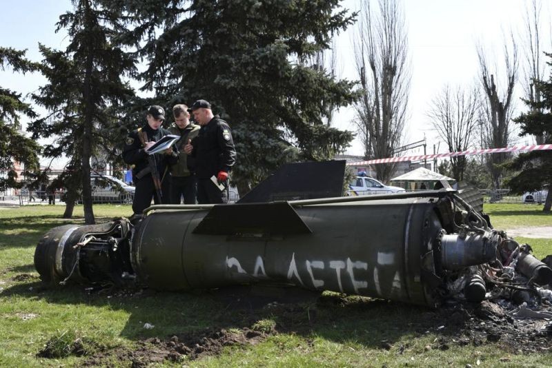 Ukrainian servicemen stand next to a fragment of a Tochka-U missile with a writing in Russian "For children" , on a grass after Russian shelling at the railway station in Kramatorsk, Ukraine, Friday, April 8, 2022. (AP Photo)