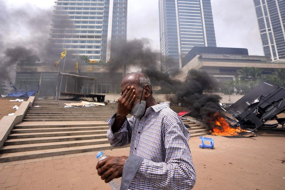 Colombo: A Sri Lankan man reacts to tear gas as he walks past the vandalized site of anti-government protests outside president's office in Colombo, Sri Lanka, Monday, May 9, 2022. Authorities deployed armed troops in the capital Colombo on Monday hours after government supporters attacked protesters who have been camped outside the offices of the country's president and prime minster, as trade unions began a ‚ÄúWeek of Protests‚Äù demanding the government change and its president to step down over the country‚Äôs worst economic crisis in memory. AP/PTI