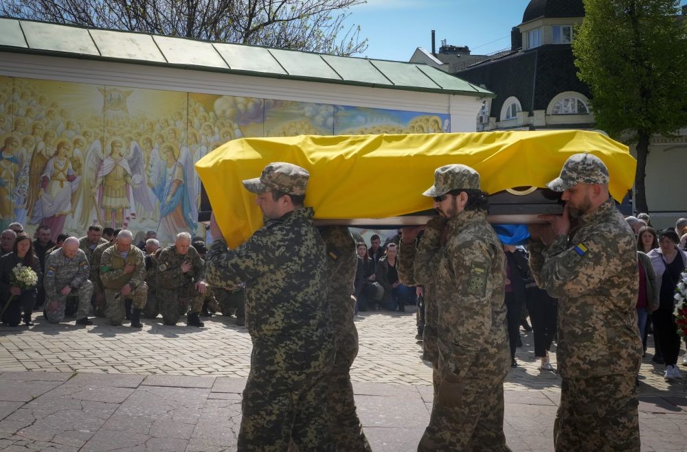Kyiv : Ukrainian soldiers carry a coffin with remains of soldier Ruslan Borovyk killed by the Russian troops in a battle,  as people kneel in the background, at St Michael cathedral in Kyiv, Ukraine, Wednesday, May 4, 2022. AP/PTI(