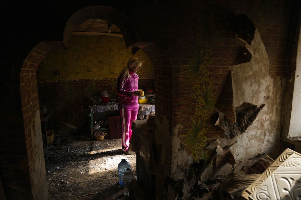 Iryna Martsyniuk, 50, collects belongings from her house, heavily damaged after a Russian bombing in Velyka Kostromka village, Ukraine, Thursday, May 19, 2022. Martsyniuk and her three young children were at home when the attack occurred in the village, a few kilometres from the front lines, but they all survived unharmed. (AP Photo/Francisco Seco)(