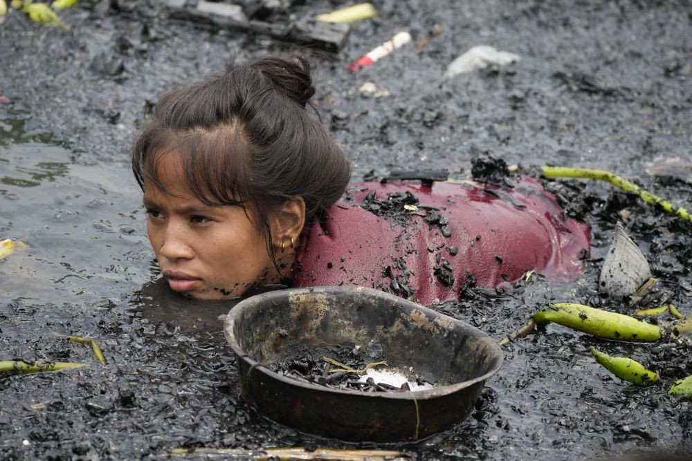 A woman searches for nails and other metal scraps from remains of burned houses that were gutted during a fire at a poor bayside village in the district of Tondo, Manila, Philippines on Friday, May 20, 2022. Investigators said about 300 families became homeless after the fire that happened Thursday night. AP/PTI