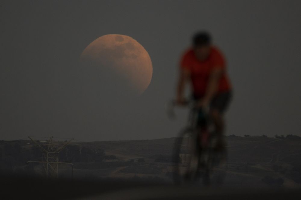 Irwindale: A lunar eclipse is seen behind a cyclist during the first blood moon of the year, in Irwindale, Calif., Sunday, May 15, 2022. AP/PTI