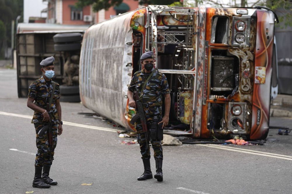 Colombo : Sri Lankan soldiers stand guard next to burnt buses a day after clashes between government supporters and anti-government protesters in Colombo, Sri Lanka, Tuesday, May 10, 2022. Defying a nationwide curfew in Sri Lanka, several hundred protesters continued to chant slogans against the government Tuesday, a day after violent clashes saw the resignation of the prime minister who is blamed, along with his brother, the president, for leading the country into its worst economic crisis in decades. AP/PTI
