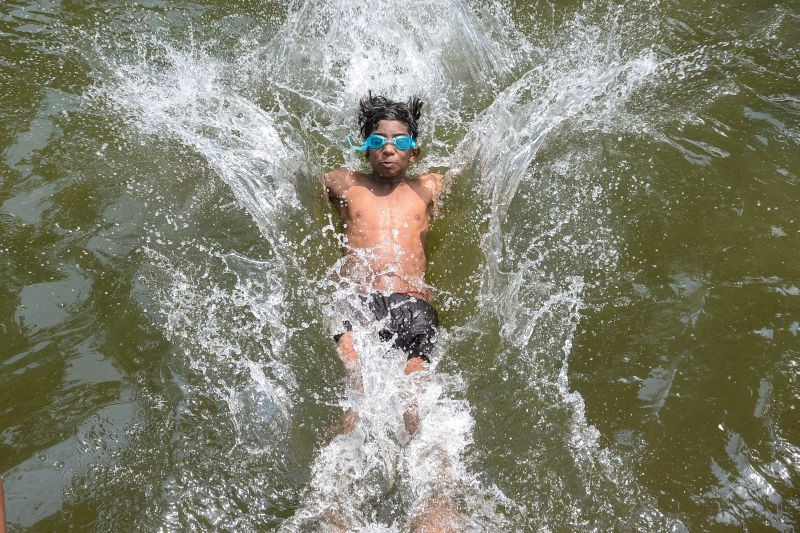 A young boy swims in the water of a canal to beat the heat on a hot summer afternoon, in Jalandhar on May 11, 2022. (PTI Photo)
