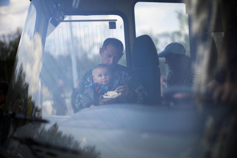 A man feeds a child as they arrive by bus at a reception center for displaced people in Zaporizhzhia, Ukraine, Monday, May 2, 2022. Thousands of Ukrainian continue to leave Russian occupied areas. (AP Photo)