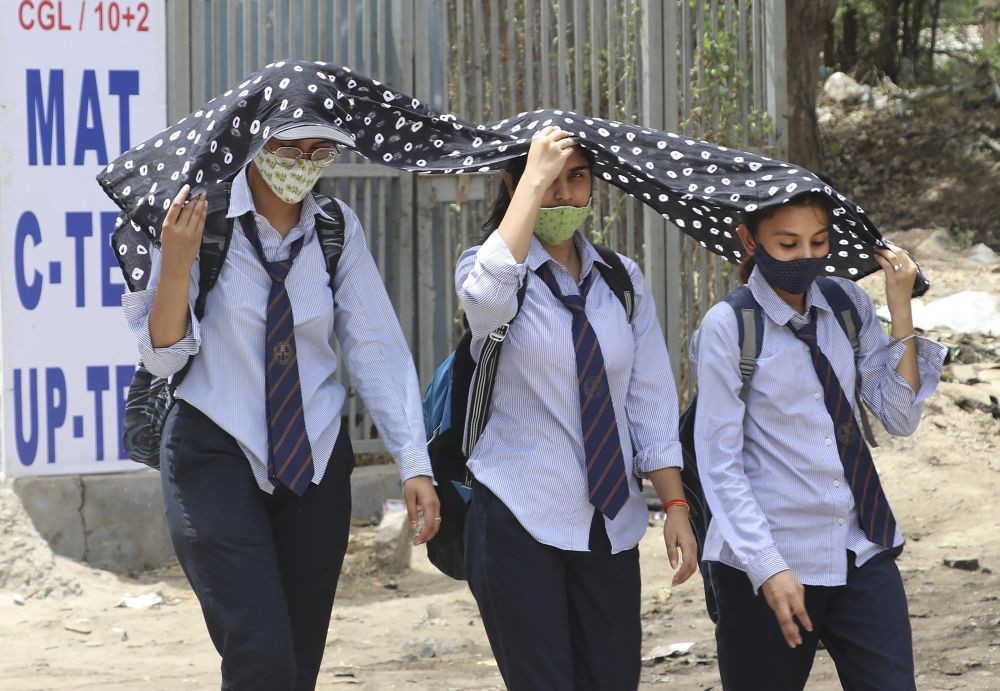 Mathura: Students cover themselves with a scarf on a hot summer day, in Mathura, Friday, May 20, 2022. (PTI Photo)