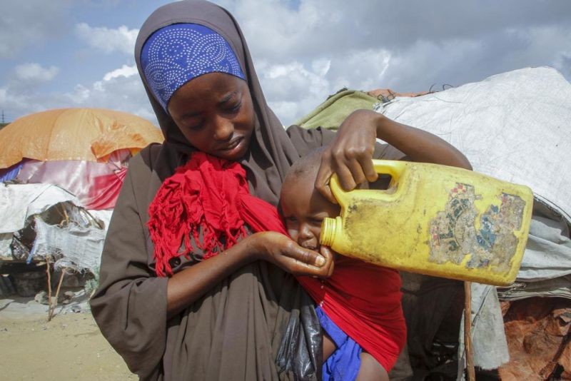 A Somali woman who fled drought-stricken areas gives water to her baby from a plastic container at a camp for the displaced on the outskirts of Mogadishu, Somalia on June 4, 2022. Deaths have begun in the region's most parched drought in decades and previously unreported data show nearly 450 deaths this year at malnutrition treatment centers in Somalia alone. (AP File Photo)