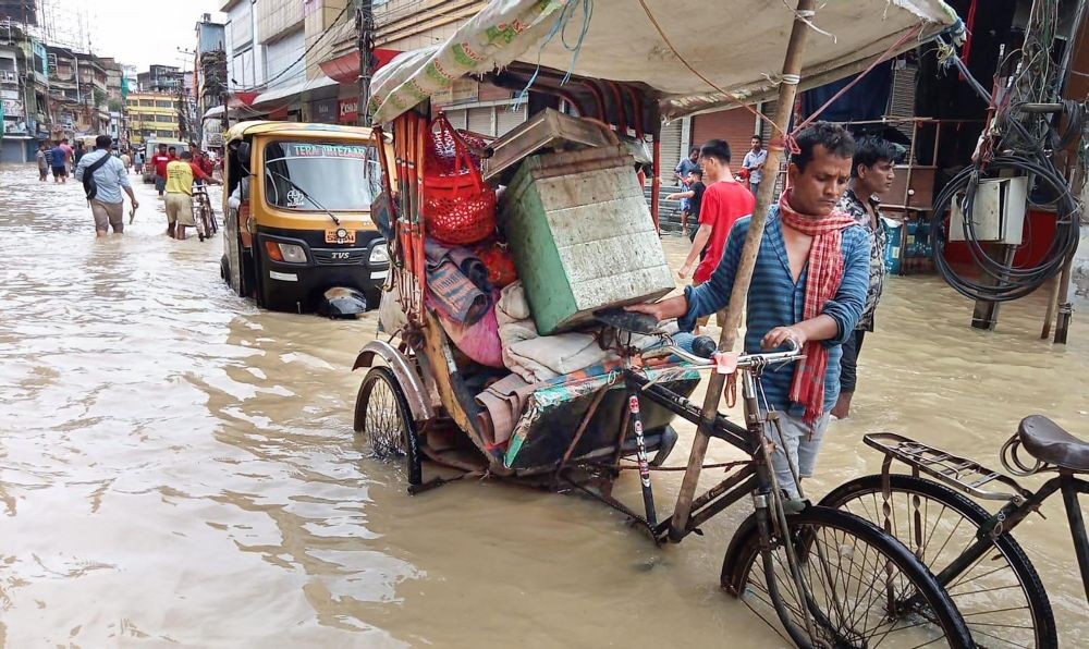 Silchar: Commuters wade through a flooded road after incessant rainfall, in Silchar, Tuesday, June 21, 2022. (PTI Photo)(