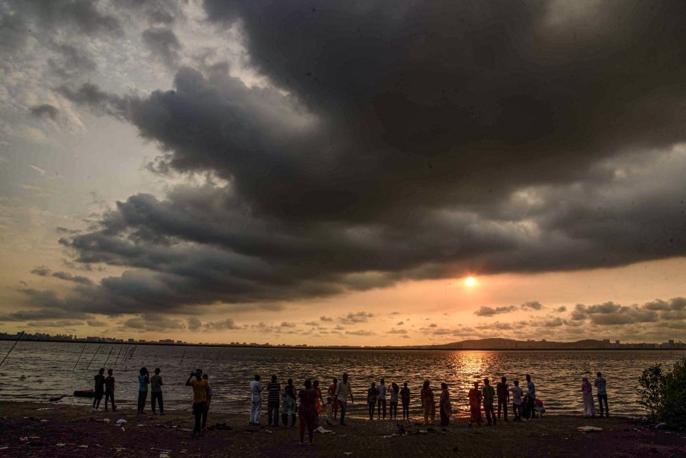 Navi Mumbai: People watch the setting sun as dark clouds hover in the sky during monsoon season, at Sagar Vihar Waterfront in Navi Mumbai, Thursday, June 23, 2022. (PTI Photo)(