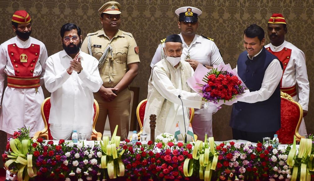 Mumbai: Newly elected Maharashtra Deputy Chief Minister Devendra Fadnavis being presented a bouquet by Governor Bhagat Singh Koshyari during his oath-taking ceremony, at Raj Bhavan in Mumbai, Thursday, June 30, 2022. Maharashtra Chief Minister Eknath Shinde is also seen. (PTI Photo/Shashank Parade)