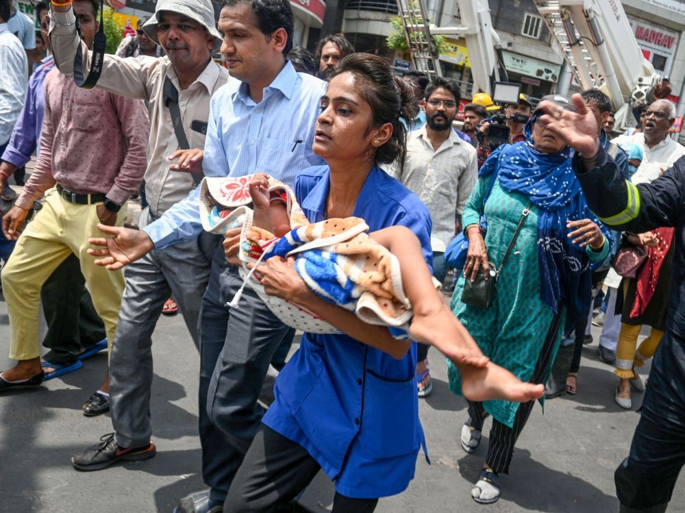 Ahmedabad: A woman carrying an infant walks away after a fire broke out at a Children's hospital in Ahmedabad, Saturday, June 25, 2022. (PTI Photo)