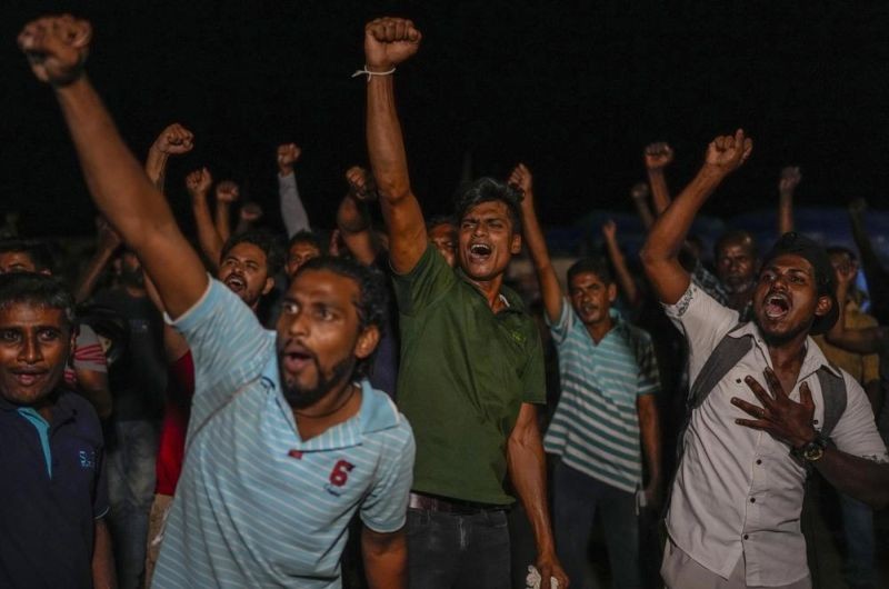 Sri Lankans celebrate as they react to early reports of President Gotabaya Rajapaksa's resignation in Colombo, Sri Lanka, Thursday, July 14, 2022. Embattled Rajapaksa fled a day earlier under pressure from demonstrators furious over the island nation’s economic collapse. He finally emailed his resignation Thursday, a day later than promised, according to an official. (AP Photo)