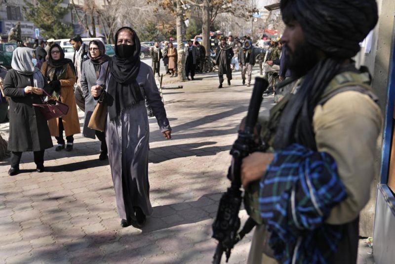 Afghan women pass next of Taliban fighter in Kabul, Afghanistan, Feb. 13, 2022. The lives of Afghan women and girls are being destroyed by the Taliban’s crackdown on their human rights, said Amnesty International in a new report Wednesday, July 27, 2022. The London-based watchdog criticized Taliban authorities saying that since Taliban took control of the country in August 2021, they have violated women’s and girls’ rights to education, work and free movement. (AP File Photo)