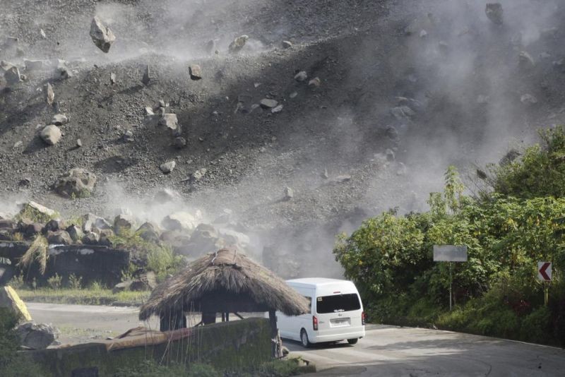 Boulders fall as a vehicle negotiates a road during an earthquake in Bauko, Mountain Province, Philippines on Wednesday July 27, 2022. A strong earthquake left some people dead and injured dozens in the northern Philippines on Wednesday, where the temblor set off small landslides and damaged buildings and churches and prompted terrified crowds and hospital patients in the capital to rush outdoors. One passenger was injured after a boulder hit the vehicle. (AP Photo)