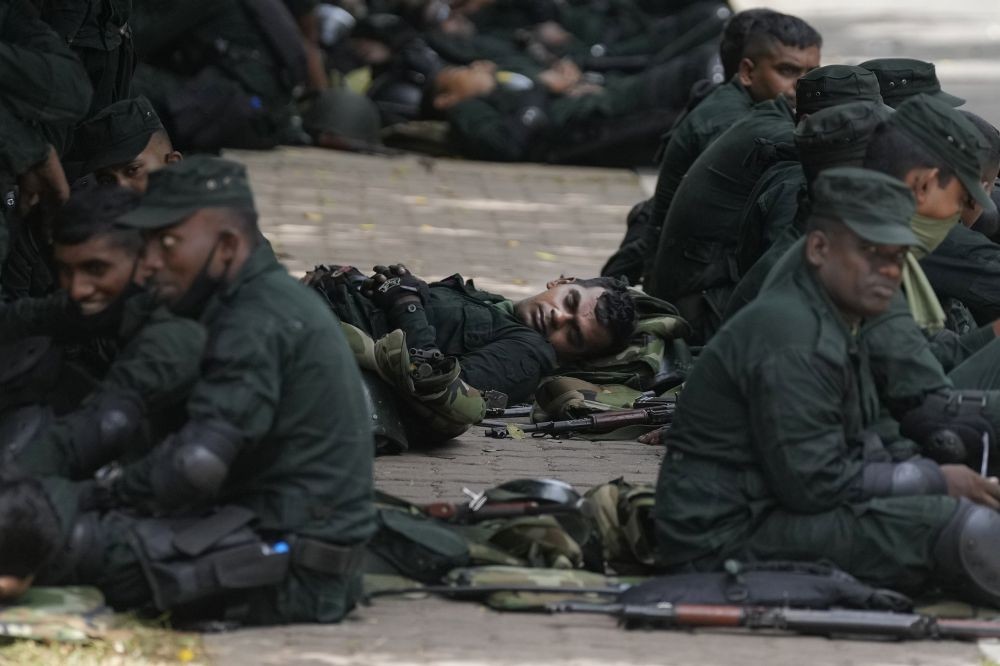 Army soldiers rest on the sidewalk of a barricaded road that leads to the parliament in Colombo, Sri Lanka, Thursday, July 14, 2022. Sri Lankan protesters began to retreat from government buildings they had seized and military troops reinforced security at the Parliament on Thursday, establishing a tenuous calm in a country in both economic meltdown and political limbo. AP/PTI