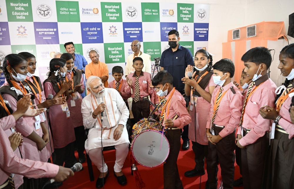PM interacts with school students at the inauguration of 62nd ‘Akshay Patra Mid-Day Meal’ Kitchen building, in Varanasi, Uttar Pradesh on July 07, 2022. (PIB Photo)