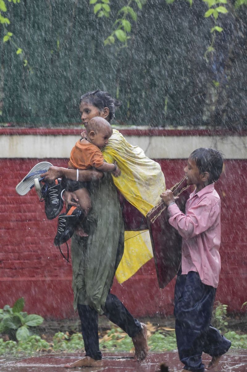 New Delhi: People look for shelter during monsoon rain in New Delhi, Monday, July 11, 2022. (PTI Photo/Kamal Kishore)