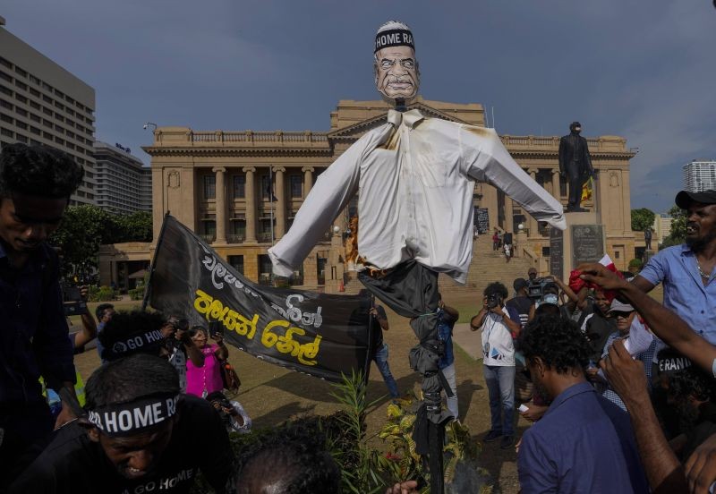 Protestors burn an effigy of acting President and Prime Minister Ranil Wickremesinghe outside the president's office as they demand his resignation in Colombo, Sri Lanka on July 19, 2022. Banner on left says " Go home before you are chased." (AP/PTI Photo)