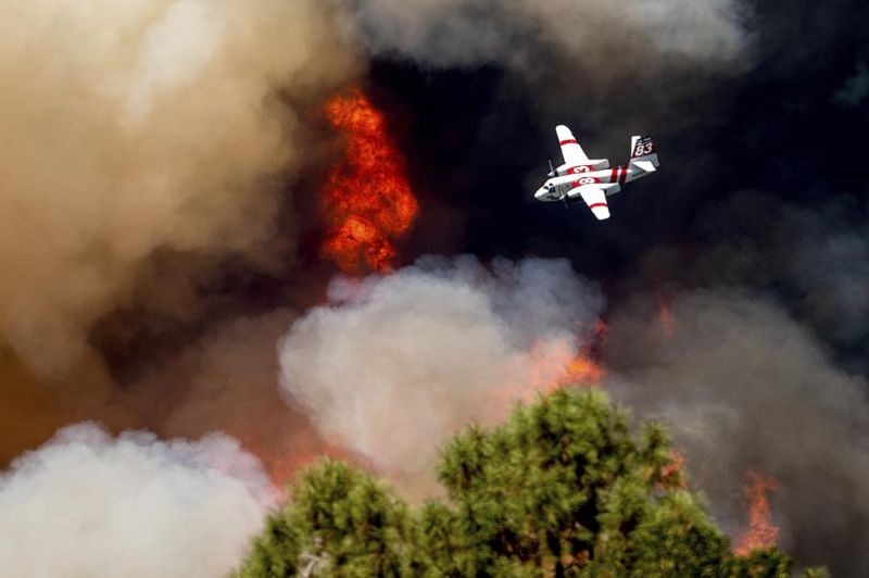 An air tanker flies past flames while battling the Oak Fire in Mariposa County, Calif., Sunday, July 24, 2022. Wildfires, floods and soaring temperatures have made climate change real to many Americans. Yet a sizeable number continue to dismiss the scientific consensus that human activity is to blame. That's in part because of a decades-long campaign by fossil fuel companies to muddy the facts and promote fringe explanations. (AP File Photo)