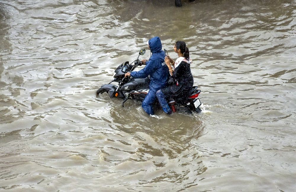 Rajkot: People riding a motorcycle wade through the waterlogged Ring Road after monsoon rains, in Rajkot, Tuesday, July 12, 2022. (PTI Photo)