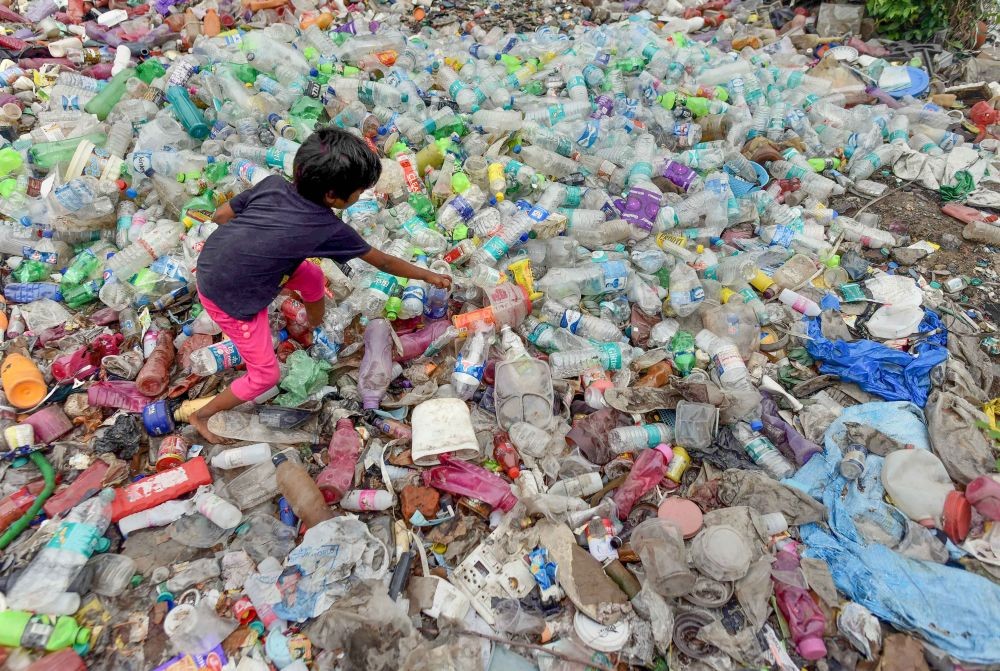 Prayagraj: A girl searches for plastic bottles at a garbage dump site in Prayagraj, Saturday, July 02, 2022. The government has banned the manufacture, import, stocking, distribution, sale, and use of all identified single-use plastic items, which have low utility and high littering potential with effect from July 1, 2022. (PTI Photo)