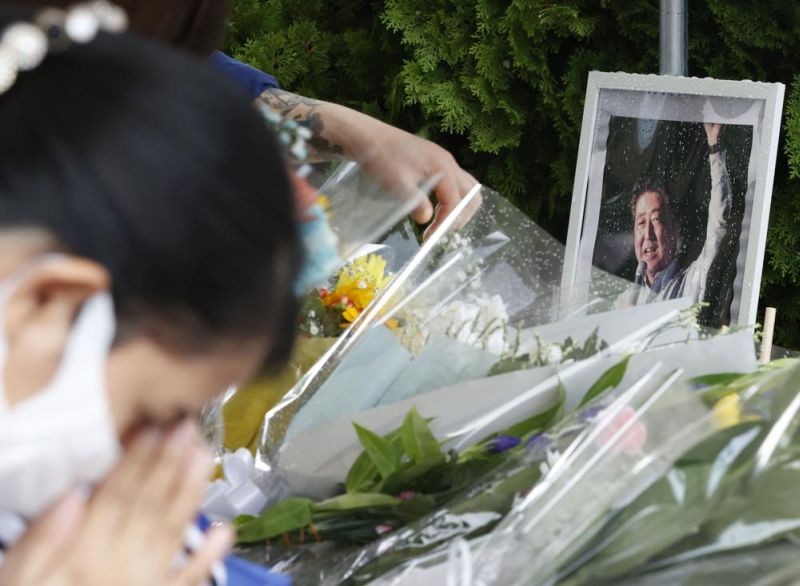 A photo of former Prime Minister Shinzo Abe is displayed on a makeshift memorial near the scene where Abe was fatally shot while delivering his speech to support a Liberal Democratic Party's candidate on Friday, in Nara on July 9. (AP Photo)
