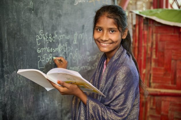 Rohingya refugee girl Rohima Akter, 13, is excited about learning to write in the Burmese language in the UNICEF learning centre in Cox's Bazar. The new curriculum provides Rohingya refugee children with formal and standardized education. (Photo Courtesy: UNICEF Bangladesh)