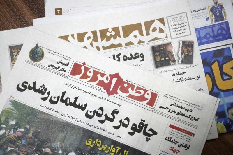The front pages of the Aug. 13 edition of the Iranian newspapers, Vatan-e Emrooz, front, with title reading in Farsi: "Knife in the neck of Salman Rushdie," and Hamshahri, rear, with title: "Attack on writer of Satanic Verses," are pictured in Tehran Saturday, Aug. 13, 2022. Rushdie, whose novel “The Satanic Verses” drew death threats from Iran’s leader in the 1980s, was stabbed in the neck and abdomen Friday by a man who rushed the stage as the author was about to give a lecture in western New York. (AP Photo)