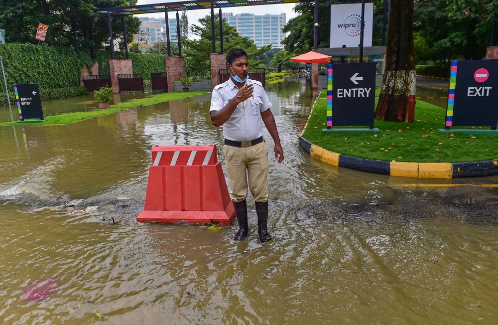 Bengaluru: A traffic police personnel regulates movement of traffic on a waterlogged road after heavy monsoon rains, near Wipro Technologies office in Bengaluru, Tuesday, Aug. 30, 2022. (PTI Photo/Shailendra Bhojak)(