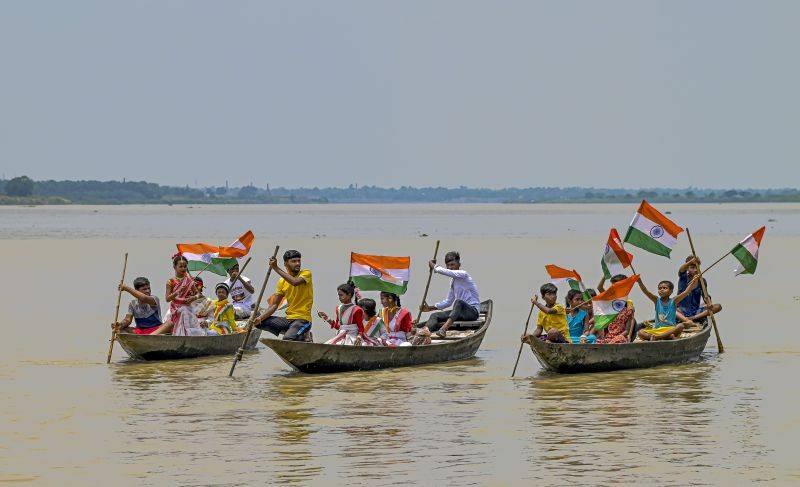 People holding the national flag sail along Hooghly river as they celebrate their Independence Day, in Nadia district on August 18, 2022. Due to a cartographic error by the British, in some villages of West Bengal bordering Bangladesh, Independence Day is celebrated on August 18. (PTI Photo)