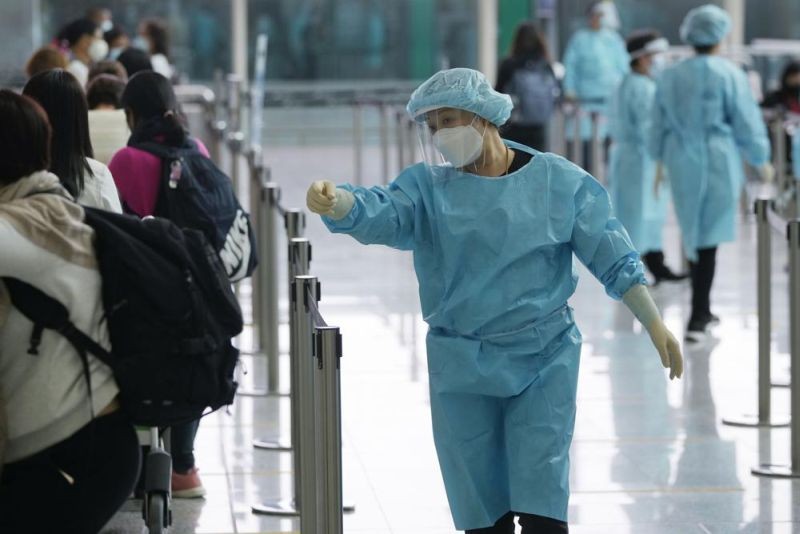 Workers wearing protective gear direct arriving passengers to quarantine hotels in the Hong Kong International Airport, Friday, April 1, 2022. Hong Kong’s government says its population has shrunk for a second year as anti-virus controls hampered the inflow of new workers and births declined, but it made no mention of an exodus of residents following a crackdown on a pro-democracy movement. (AP File Photo)
