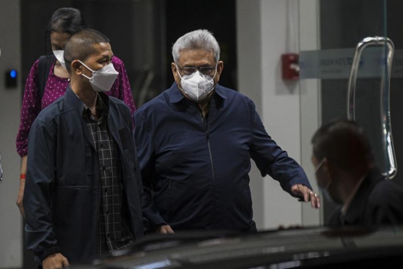 Former Sri Lankan President Gotabaya Rajapaksa, center, walks to a waiting vehicle outside the Don Mueaung airport in Bangkok, Thailand Thursday, Aug. 11, 2022. Rajapaksa, who last month fled anti-government protests in his country, has left Singapore, immigration authorities there said Thursday. (AP Photo)