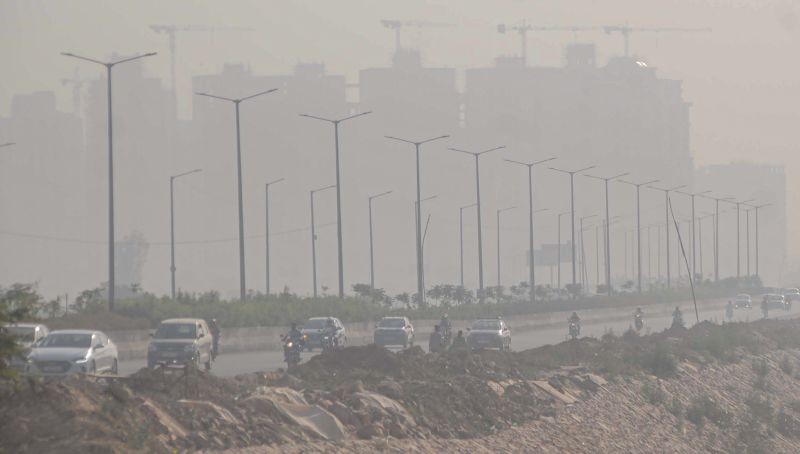 Vehicles ply on a road as smog engulfs buildings, in Greater Noida. (PTI File Photo)