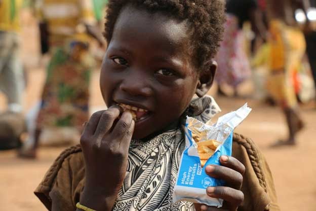A child eating WFP high-energy biscuits as part of WFP's nutrition assistance in Batangafo town, northern Central African Republic. (Photo Courtesy: WFP/Bruno Djoyo)