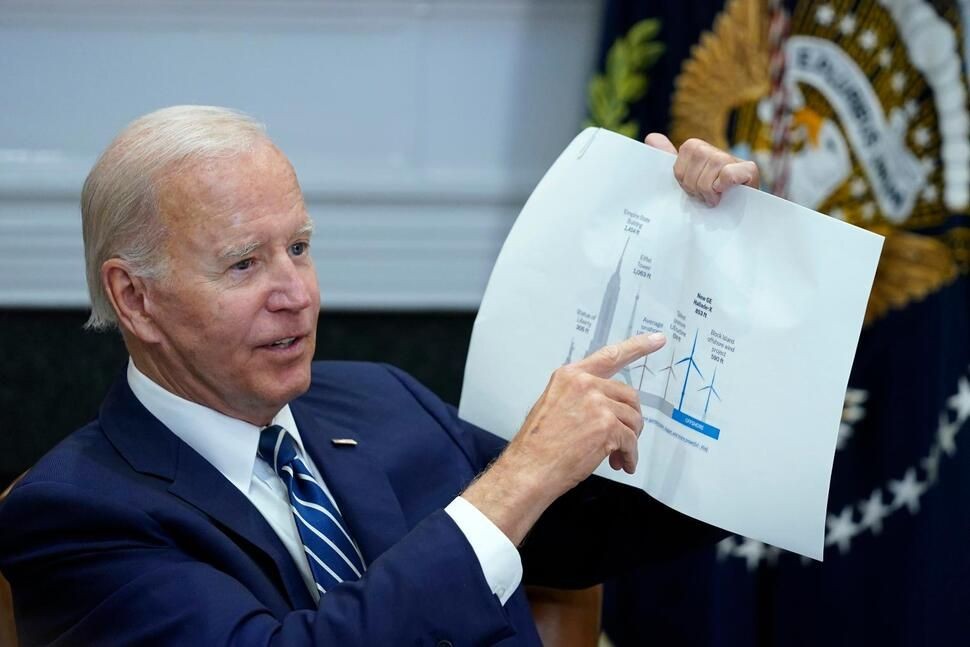 FILE - President Joe Biden shows a wind turbine size comparison chart during a meeting in the Roosevelt Room of the White House in Washington, June 23, 2022. The U.S. has renewed legitimacy on global climate issues and will be able to inspire other nations in their own emissions-reducing efforts, experts said, after the Democrats pushed their big economic bill through the Senate on Sunday, Aug. 7. (AP Photo/Susan Walsh, File) THE ASSOCIATED PRESS