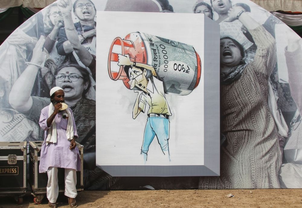 New Delhi: A Congress supporter eats in front of a poster during the 'Mehangai Par Halla Bol' rally on price rise, at Ramlila Maidan in New Delhi, Sunday, Sep. 4, 2022. (Photo: Wasim Sarvar/IANS)