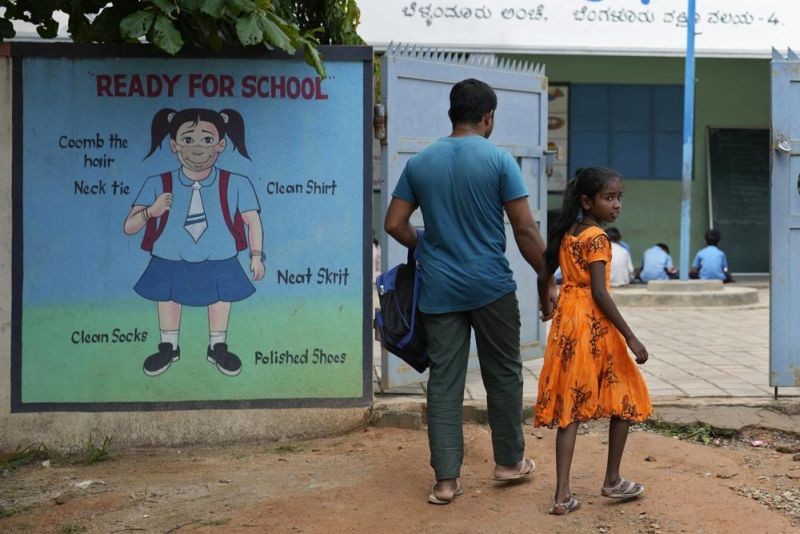 Jaidul Islam, left, arrives with his daughter Jerifa to drop her at a government school in Bengaluru on July 20, 2022. A flood in 2019 in the Darrang district of India's Assam state started Jerifa, her brother Raju and their parents on a journey that led the family from their Himalayan village to the poor neighborhood. (AP File Photo)