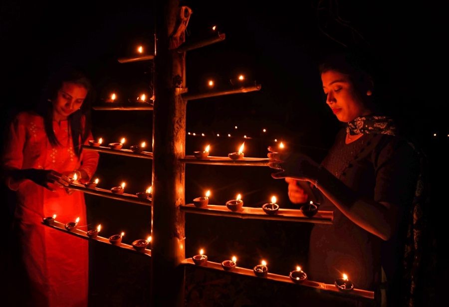 Nagaon: Women light earthen lamps on the occasion of 'Kati Bihu' or 'Kangali Bihu' festival, in Nagaon District of Assam on Oct. 18, 2022. (Photo: Anuwar hazarika/IANS)