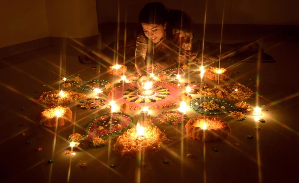 Kolkata: A girl making a rangoli with flowers, colours and earthen lights ahead of  Diwali festival in Kolkata on Saturday, October 22, 2022. (Photo:Kuntal Chakrabarty/IANS)