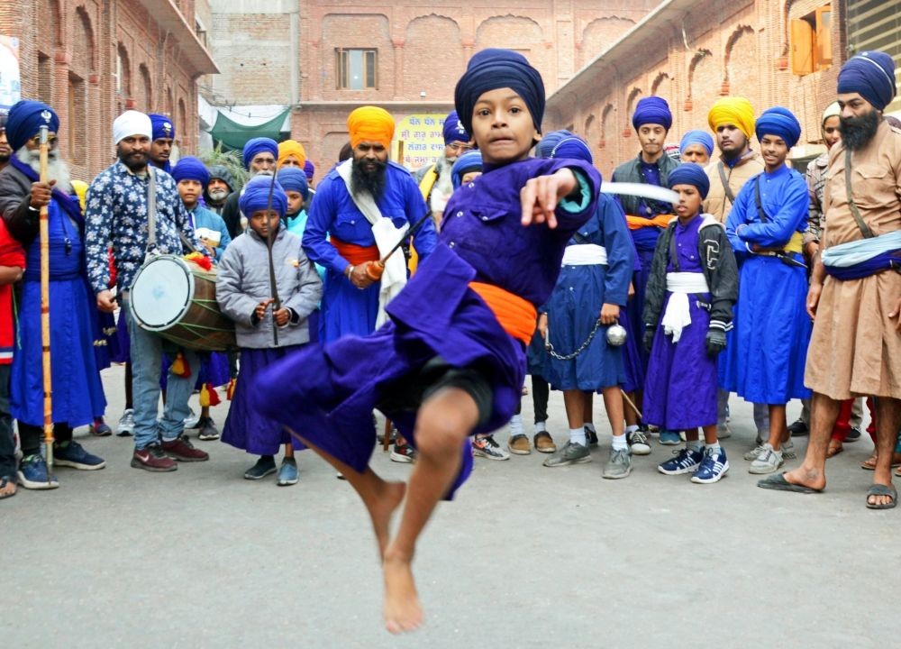 A devotee shows his skill during a 'Nagar Kirtan' taken out ahead of the birth anniversary of the 10th Sikh Guru Gobind Singh, at the Golden Temple in Amritsar on December 27, 2022. (IANS Photo)