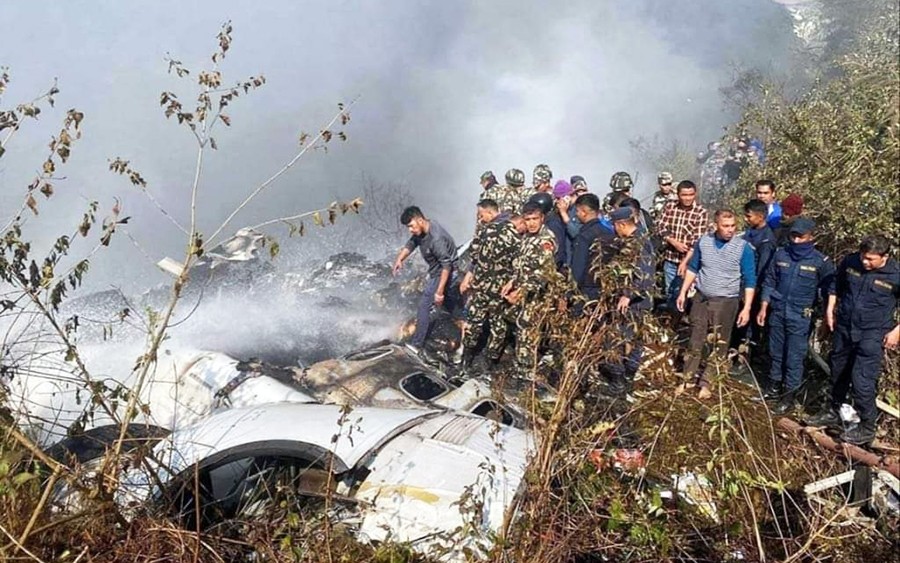 Pokhara : Locals watch the wreckage of a passenger plane in Pokhara, Nepal, Sunday, Jan.15, 2023. A passenger plane with 72 people on board crashed near Pokhara International Airport in Nepal.. (Photo:IANS)