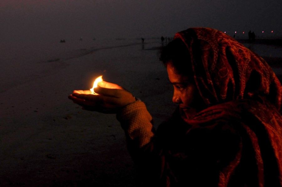 Gangasagar: A woman devotee holding an earthen lamp performs rituals at the Gangasagar Mela in Gangasagar island on Friday, January 13, 2023. (Photo: Kuntal Chakrabarty/IANS)