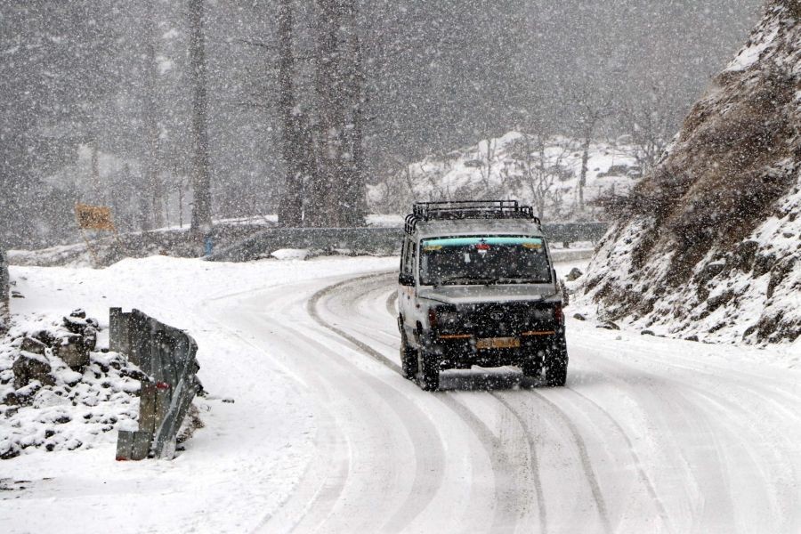 Anantnag: A vehicle makes its way through a snow-covered road during a fresh snowfall in Anantnag district  on Friday, Jan. 13, 2023. (Photo: Nisar Malik/IANS)
