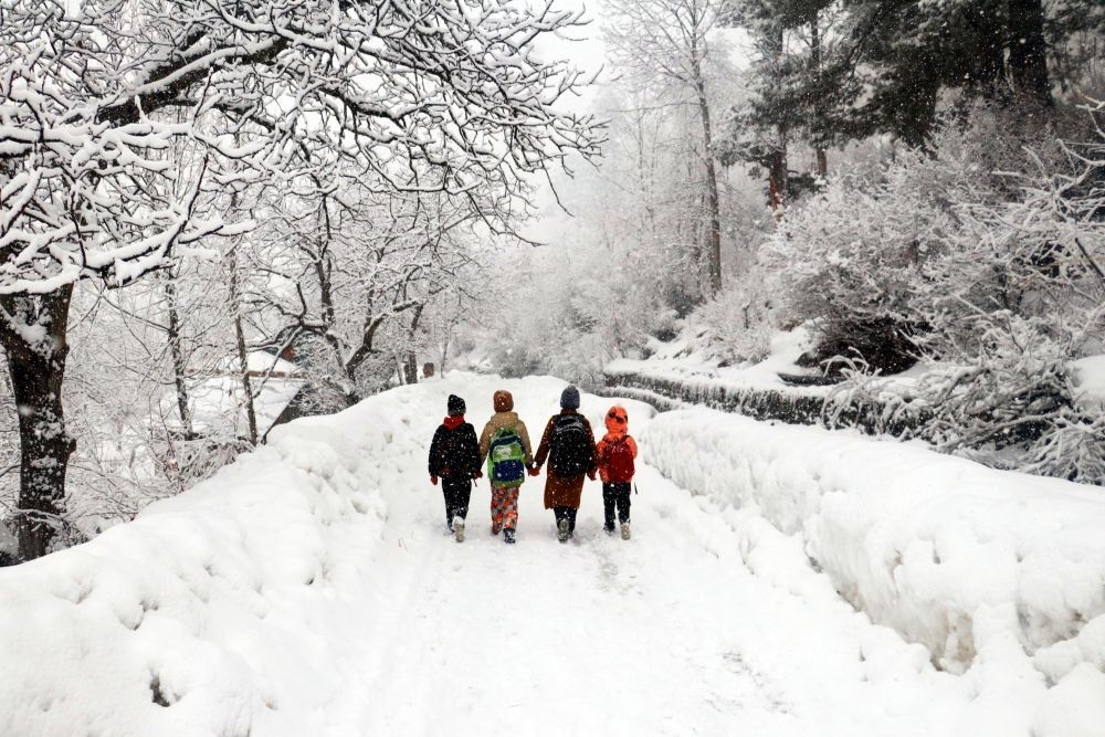 Baramulla : School students walk on a snow covered road amid heavy snowfall in Tangmarg area of Baramulla district on Saturday, Feb 11, 2023. (Photo: Nisar Malik /IANS)