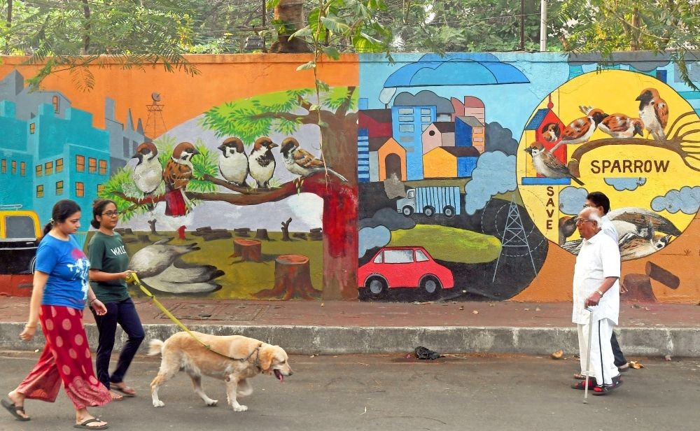 Mumbai : People walk past a painted wall featuring the theme of Sparrow, the wall was painted as a part of an awareness campaign ahead of World Sparrow Day, in Mumbai on March 18, 2023. (Photo:IANS)