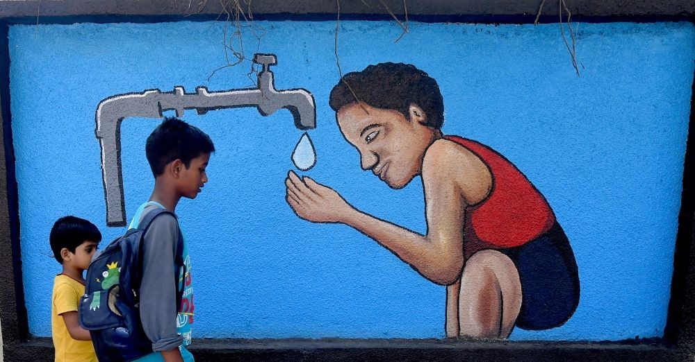 Mumbai: Two boys walk past a graffiti wall depicting a boy drinking water from a tap on the eve of World Water Day, in Mumbai on Tuesday, March 21, 2023. (Photo:IANS)